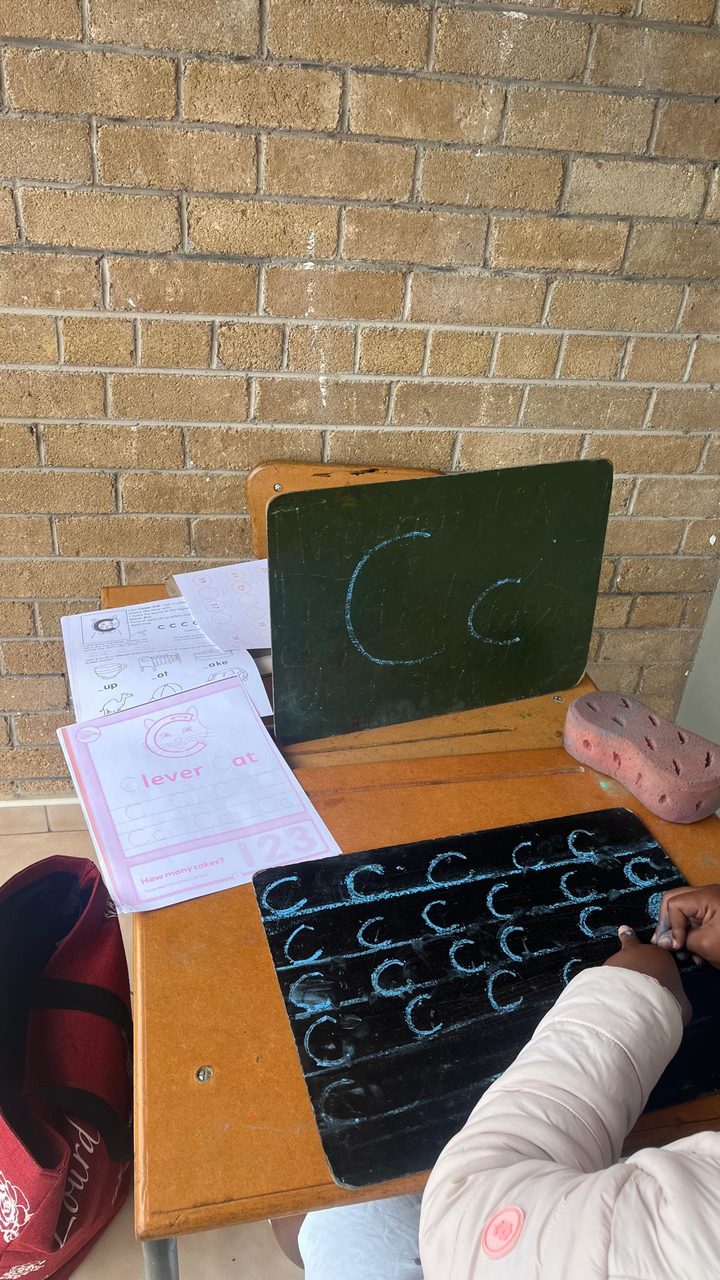 A child practicing letters on a slate